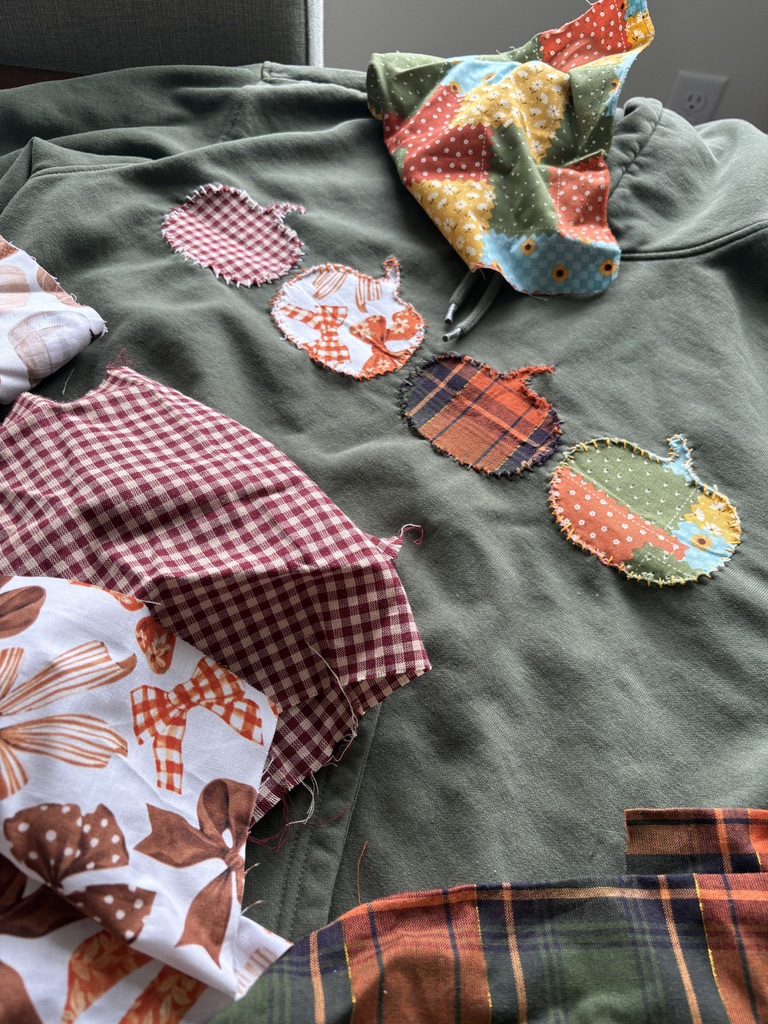 Fall pumpkin patches in plaid, gingham, and floral fabric stitched onto a green sweatshirt